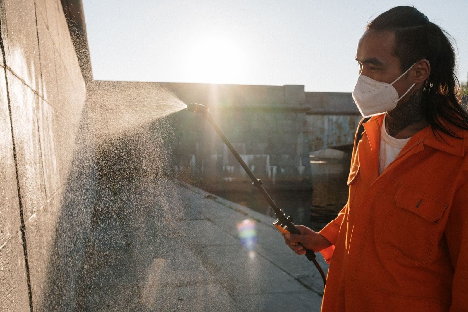 Close-up of a spray wand misting water across a concrete wall